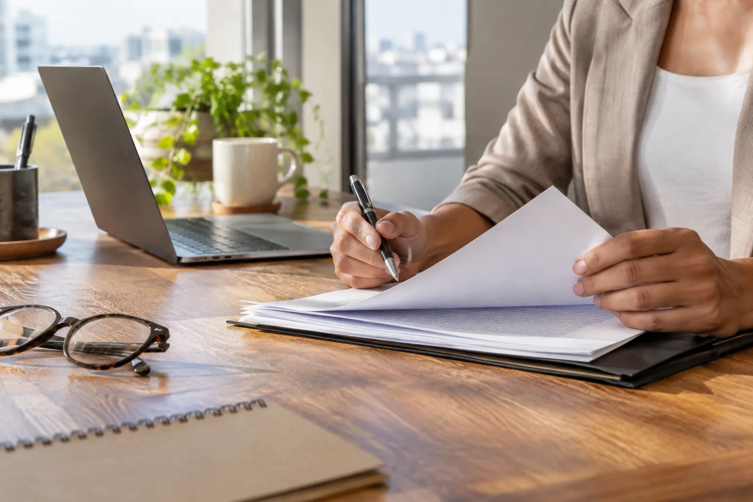 Pessoa revisando documentos sobre uma mesa de trabalho